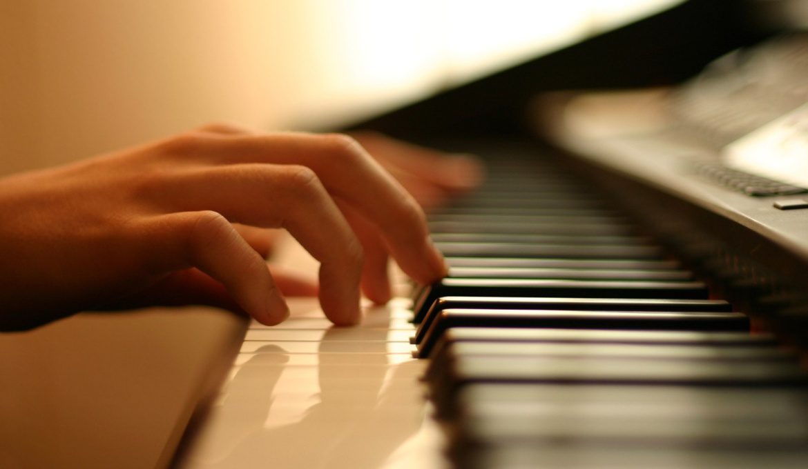 Fingers rest on the keys of an electric piano